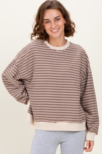 woman wearing a brown and cream striped oversized sweatshirt with long sleeves and a relaxed fit