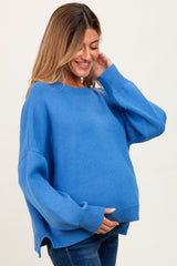 woman wearing a bright blue maternity sweater and holding her baby bump
