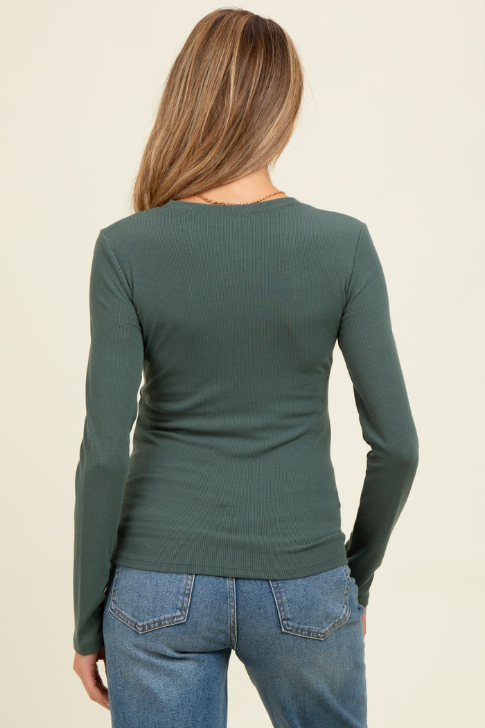 woman wearing a green long sleeve maternity top, viewed from the back, paired with blue jeans