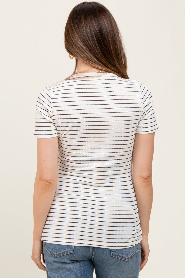 woman wearing a cream and black striped maternity top, seen from the back with a fitted style