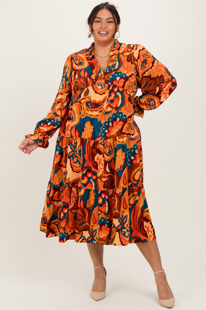 woman wearing a vibrant orange floral plus size dress with long sleeves and a tiered skirt, standing against a neutral background