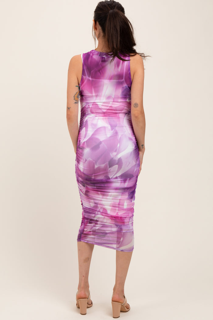 woman wearing a purple and pink floral print maternity dress with gathered details, showing her baby bump from the back
