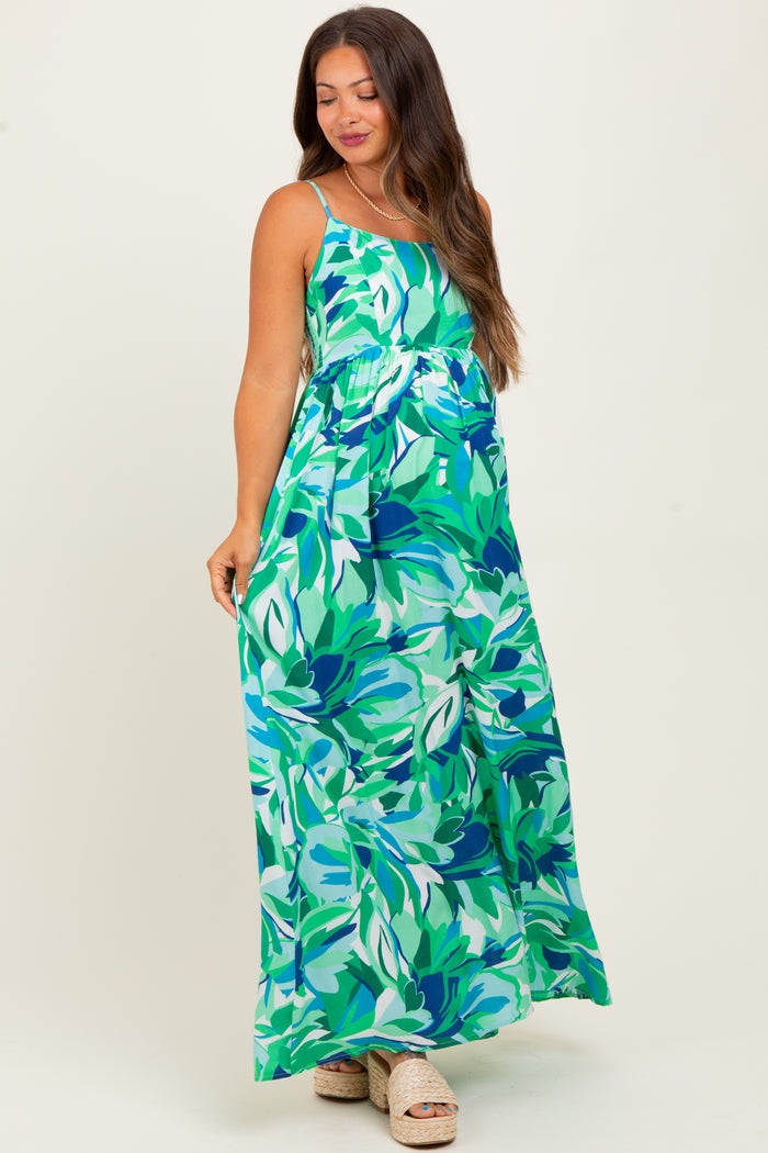 woman wearing a green floral maxi dress, showcasing her baby bump, in a maternity style