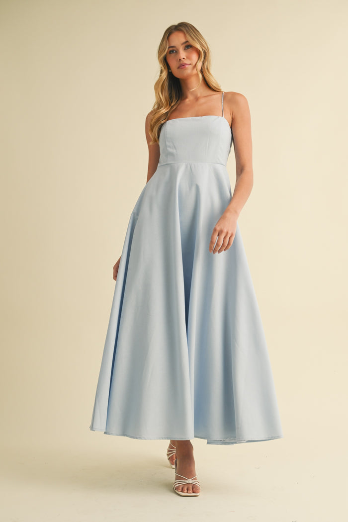 woman wearing a light blue long maxi dress with spaghetti straps and a flared skirt