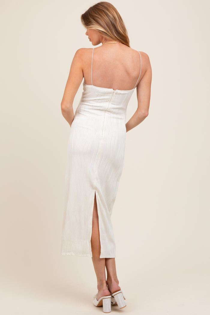 woman wearing a light beige maternity dress with a slit at the back and thin straps