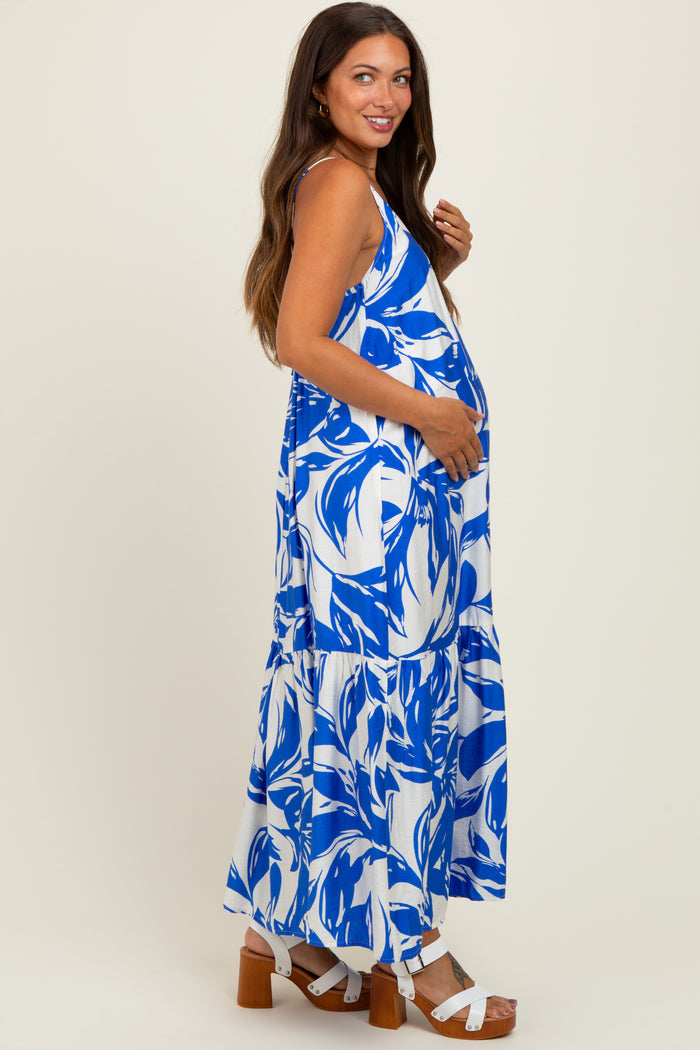 woman wearing a blue and white floral maternity maxi dress, showing her baby bump and paired with white sandals