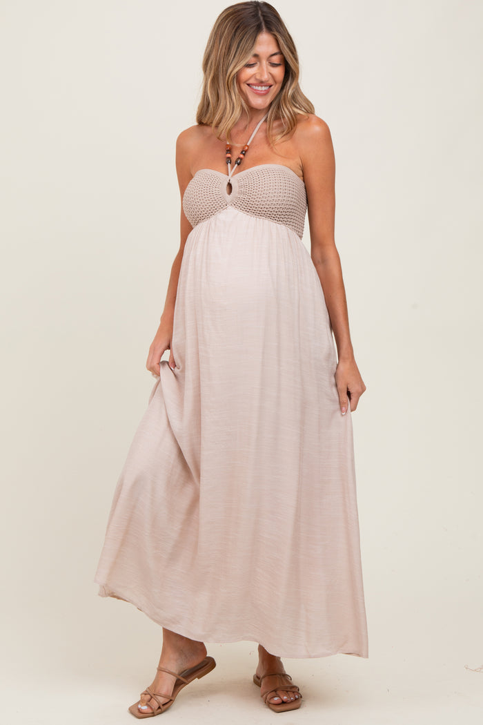 woman wearing a beige strapless maternity maxi dress with a smocked bodice and flowing skirt, showing her baby bump