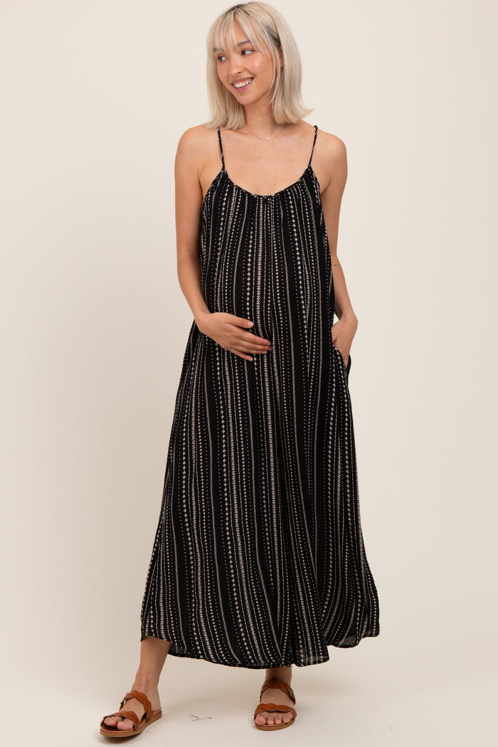 woman wearing a black and white striped maternity maxi dress with a flowing silhouette and pockets, highlighting her baby bump