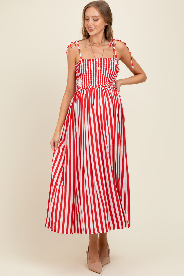 woman wearing a red and white striped maternity dress with tie shoulder straps and a smocked bodice, showing her baby bump