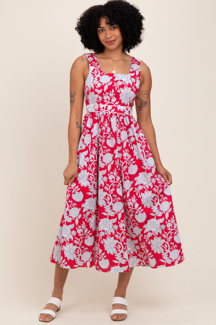 woman wearing a red floral midi dress with a fitted bodice and flared skirt, smiling against a light background