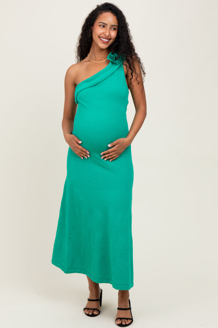 woman wearing a green one-shoulder maternity dress and holding her baby bump