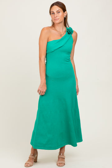 woman wearing a sleeveless green maxi dress with a floral accent on the shoulder