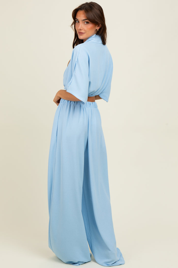 woman wearing a light blue two-piece outfit with a short-sleeve top and wide-leg pants, showing the back view