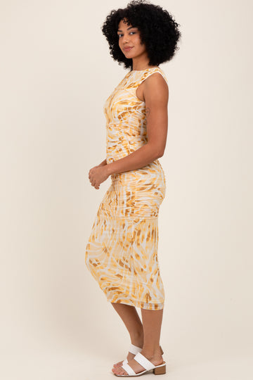 woman wearing a yellow and white tie-dye midi dress with ruching and a fitted silhouette