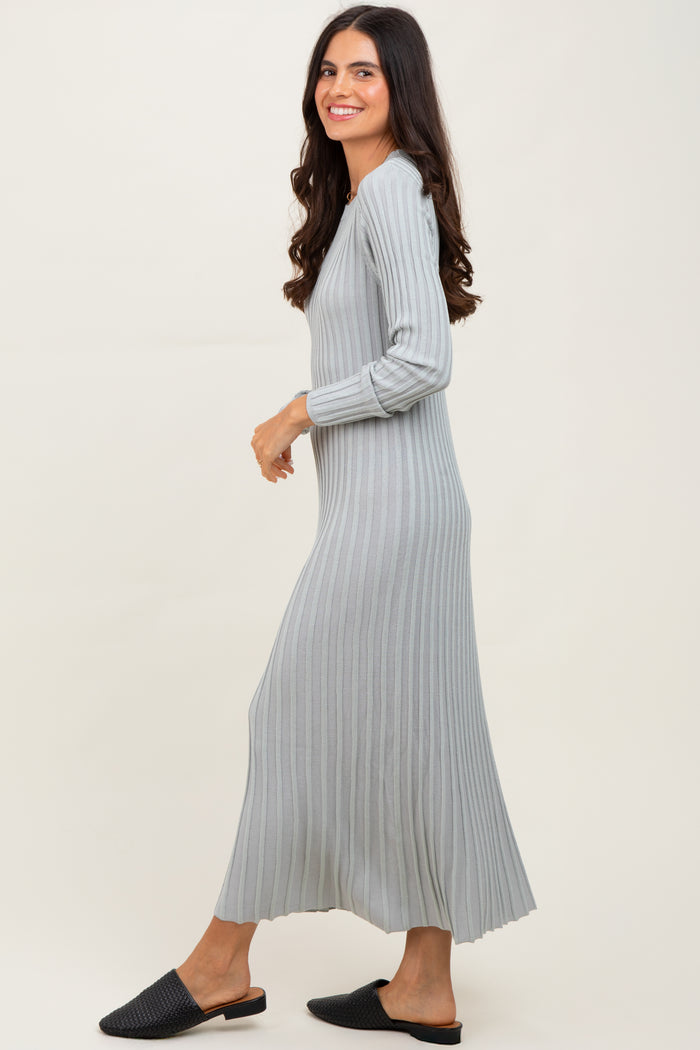 woman wearing a light gray ribbed knit maxi dress with long sleeves and side slits, standing and smiling