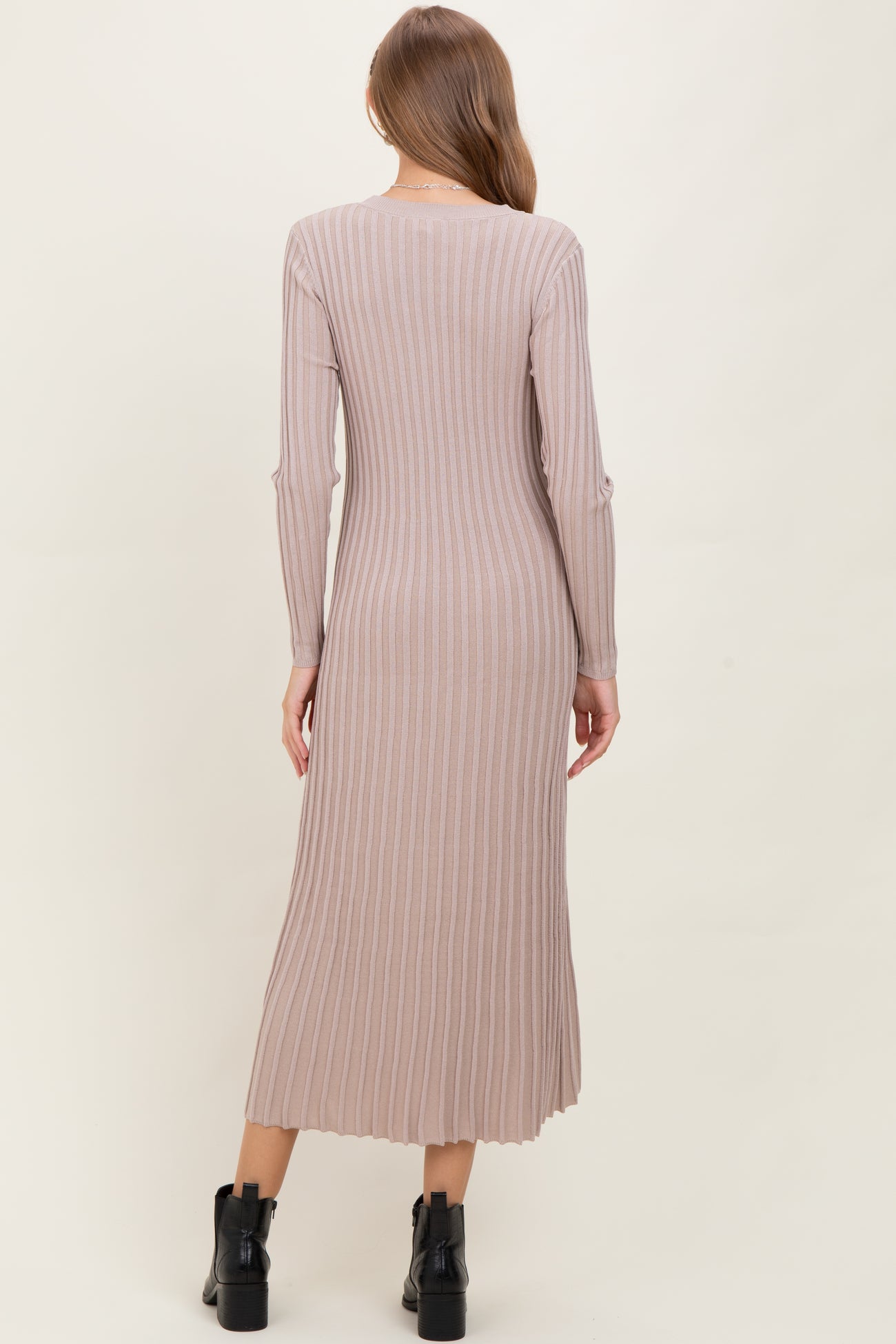 woman wearing a ribbed long sleeve beige maternity dress, showcasing a fitted silhouette and mid-calf length
