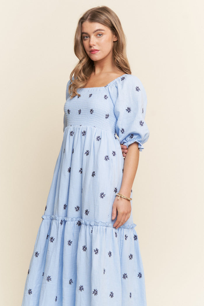 woman wearing a light blue floral embroidered maxi dress with puff sleeves and a smocked bodice