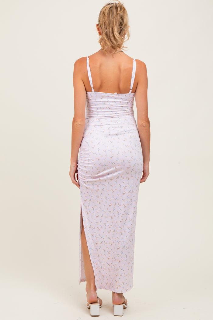 woman wearing a light pink floral maternity maxi dress with ruching and a side slit, view from the back