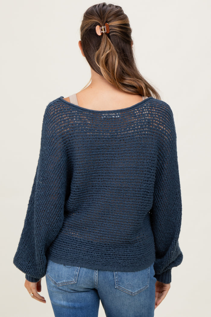 woman wearing a navy blue open-knit maternity sweater with a loose fit and bell sleeves