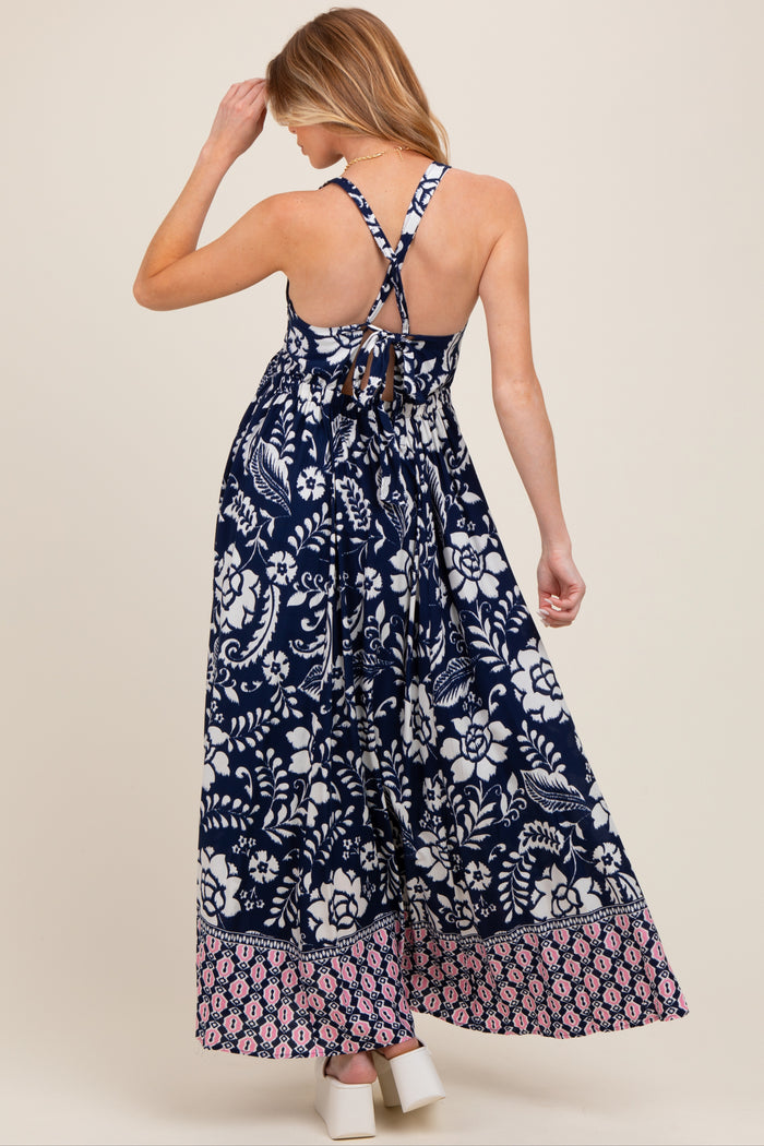 woman wearing a navy blue floral print maternity maxi dress with crisscross back straps and a flowy silhouette