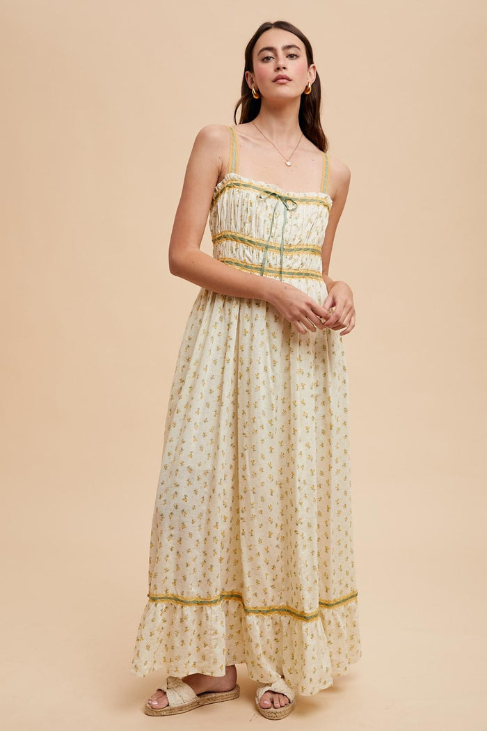 woman wearing a floral maxi dress with spaghetti straps and ruffle details, set against a neutral background