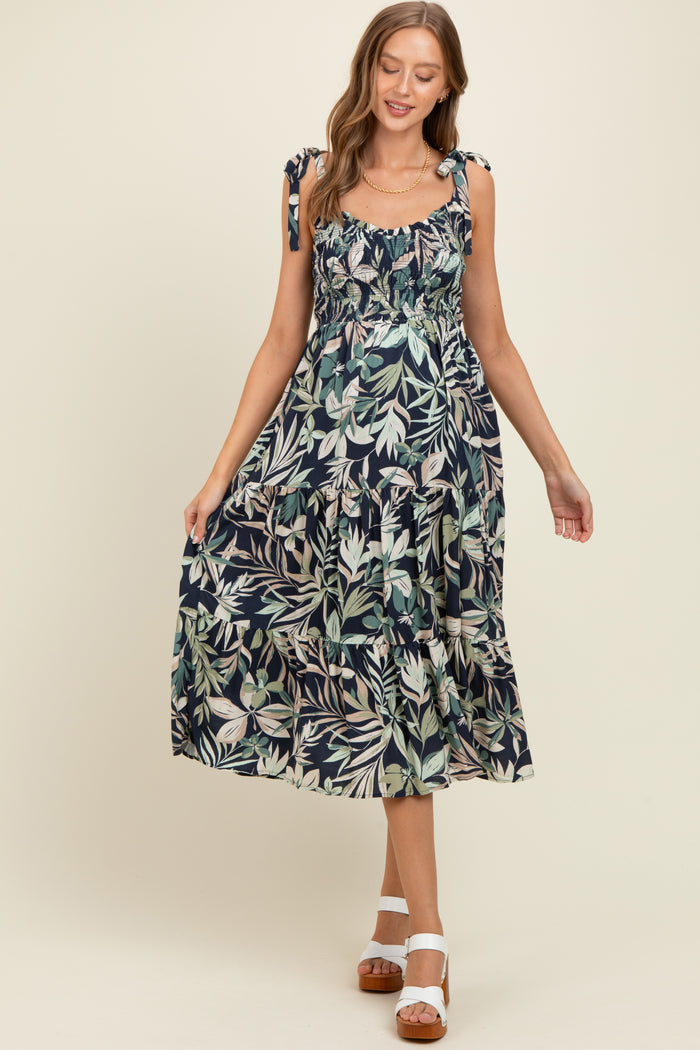 woman wearing a navy blue floral maternity maxi dress with tie shoulder straps and a tiered skirt