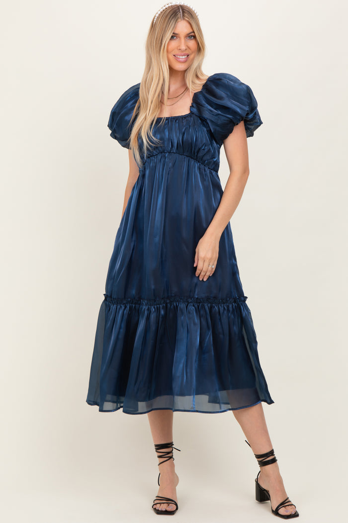 woman wearing a navy blue puff sleeve maxi dress with a tiered skirt and strappy black heels