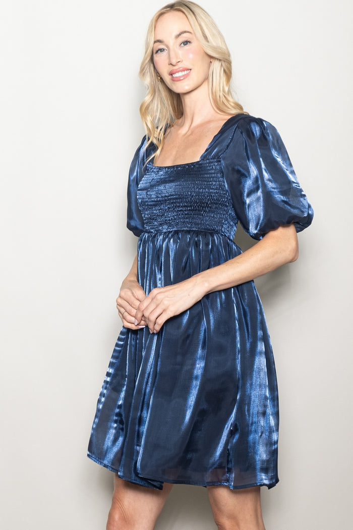 woman wearing a navy blue short puff sleeve dress with a smocked bodice and a flared skirt