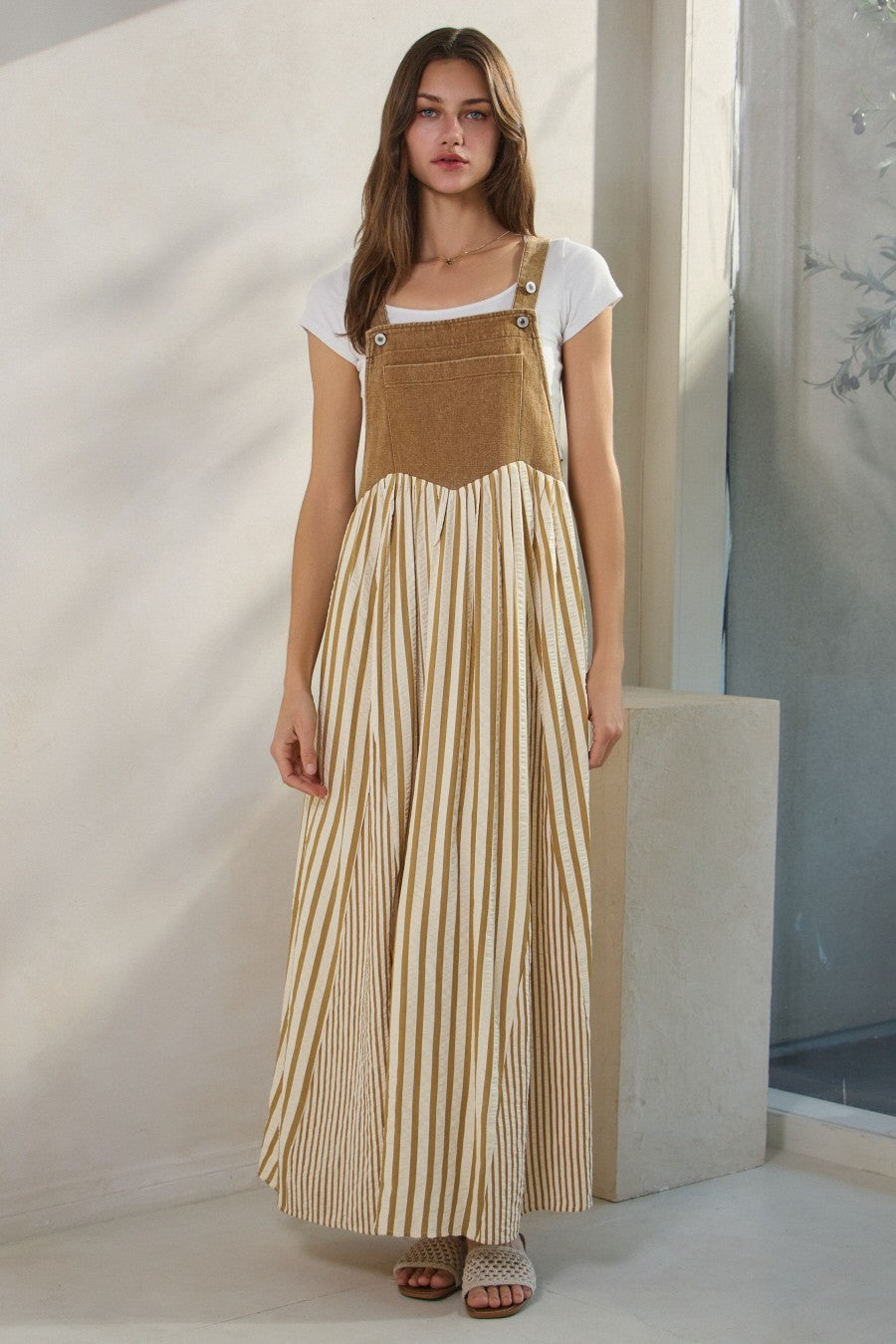 woman wearing a long striped tan and white maxi dress with buttons and a fitted top over a short sleeve white tee