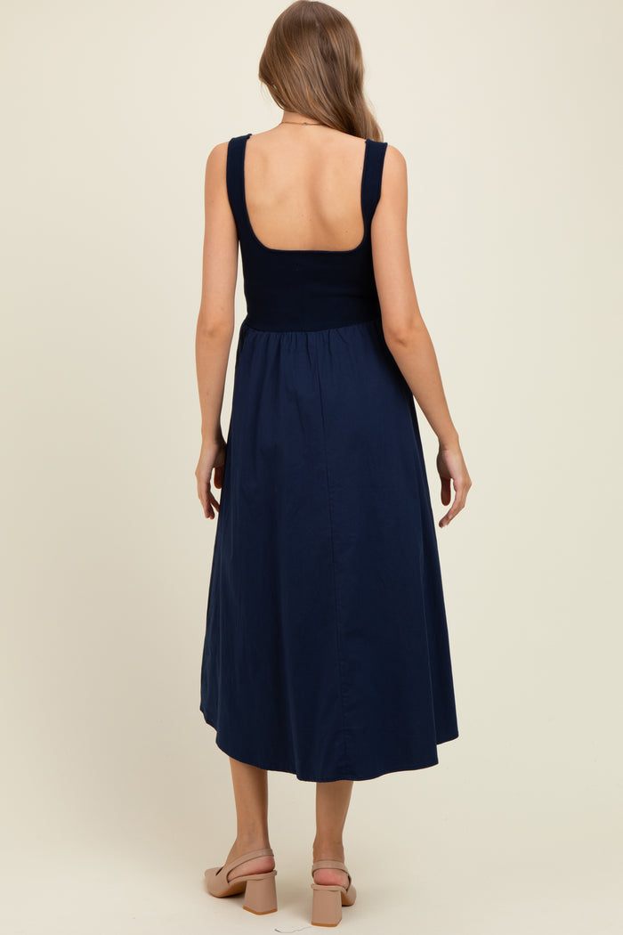 woman wearing a navy blue maternity dress with a sleeveless design and a fitted bodice, showing a baby bump
