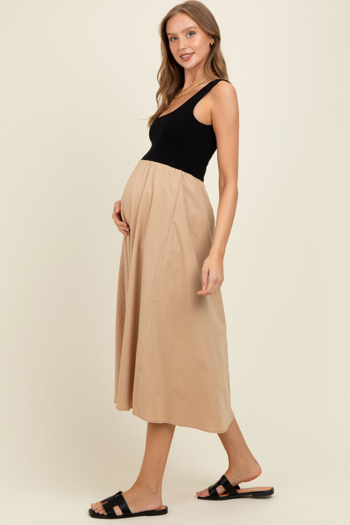 woman wearing a black and beige maternity dress, showcasing her baby bump, with a flowy skirt and sandals.