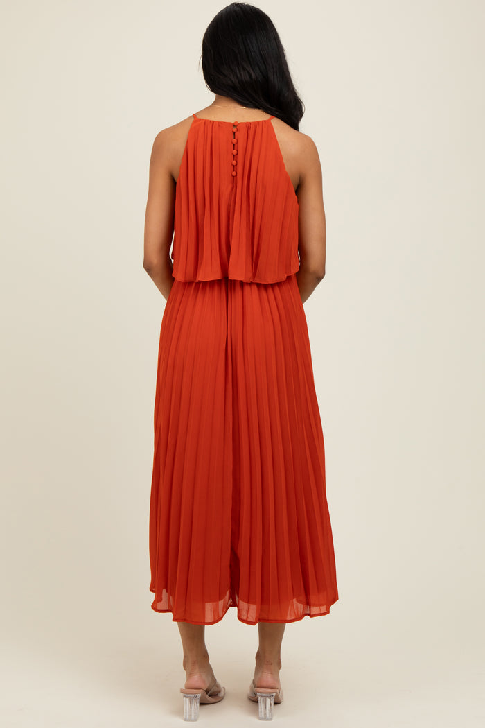 woman wearing an orange pleated maxi dress with a layered back design and transparent heels