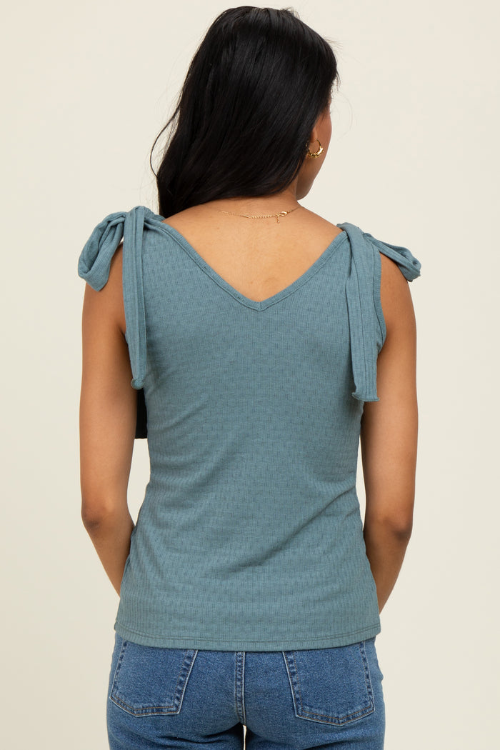 woman wearing a teal sleeveless top with bow details on the shoulders and a v-neckline, viewed from the back