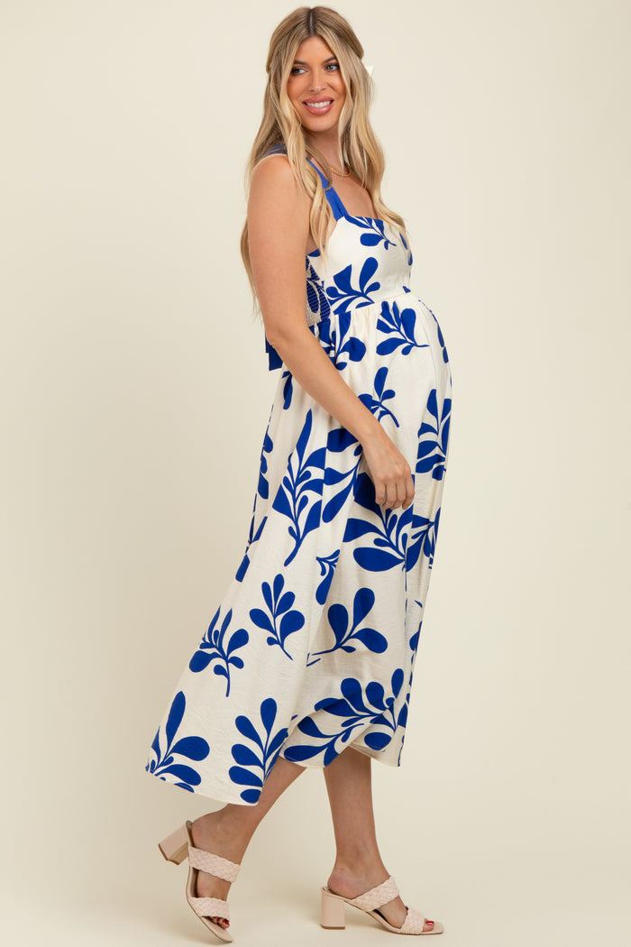 woman wearing a white maternity dress with blue floral print and a fitted waist, showing baby bump
