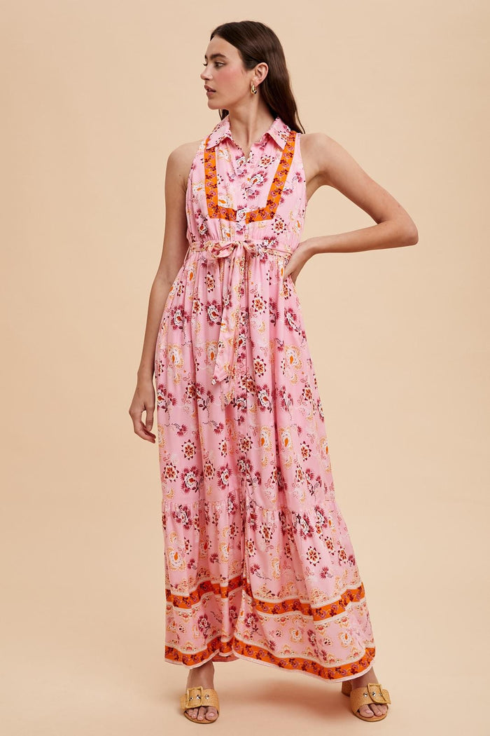 woman wearing a pink floral maxi dress with a tied waist and a collar, styled for a summer look