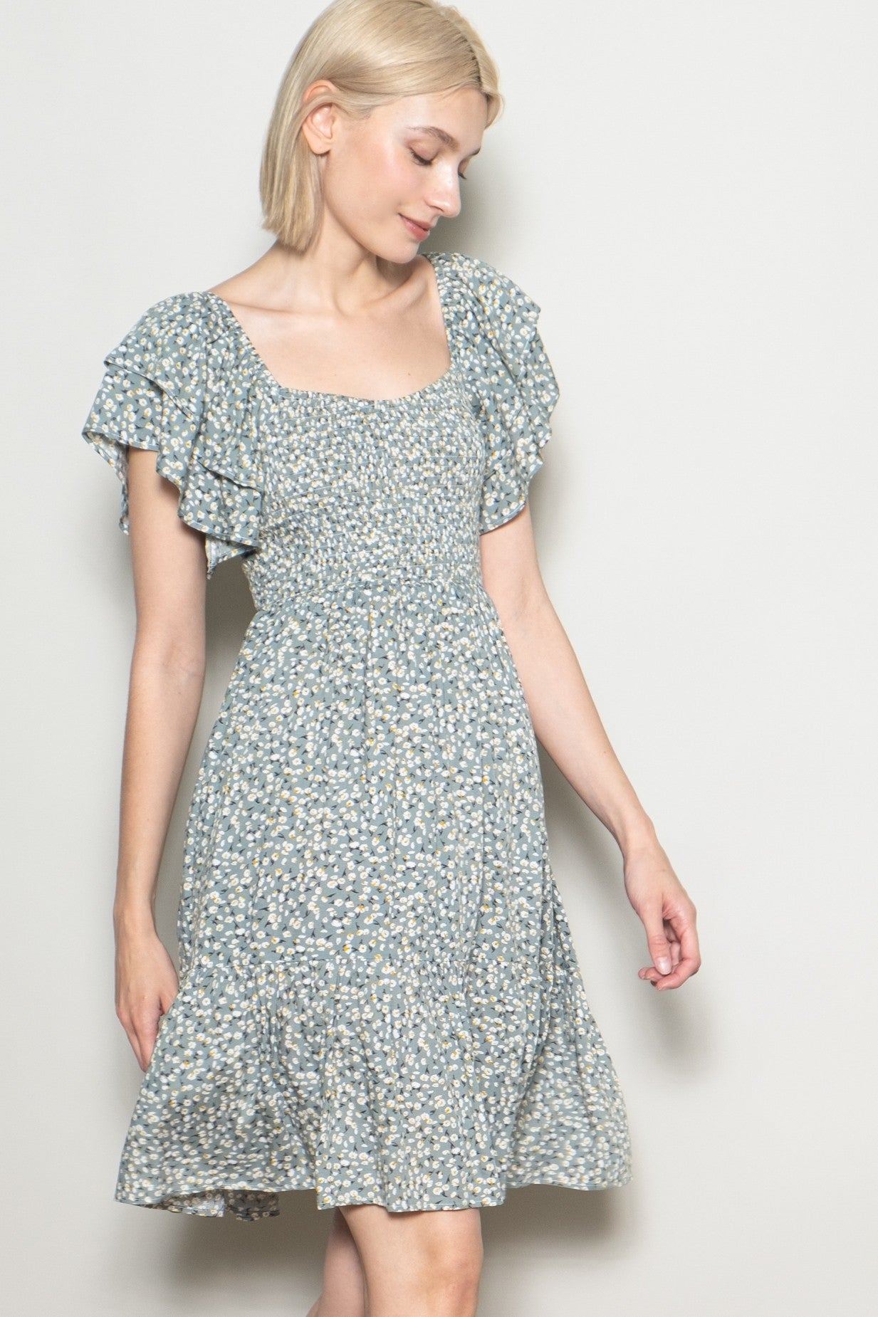 woman wearing a light blue floral short dress with ruffled sleeves and a square neckline