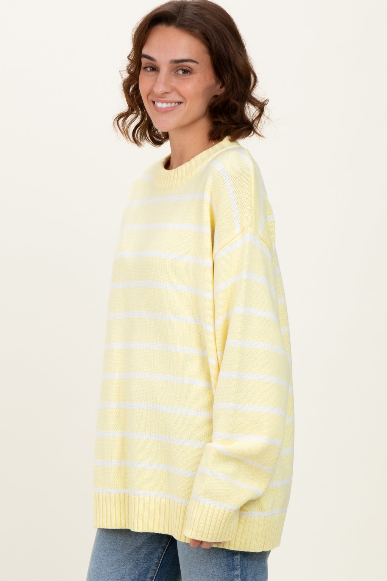 woman wearing a yellow and white striped oversized sweater and blue jeans