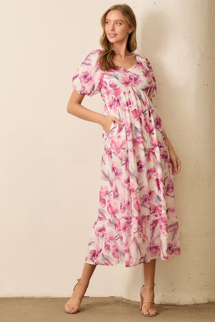 woman wearing a floral pink and white maxi dress with puff sleeves and pockets