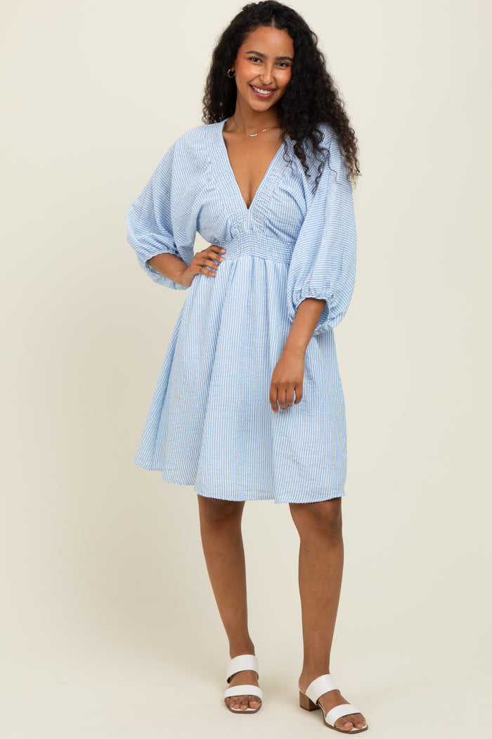 woman wearing a light blue striped short sleeve dress with a deep v-neck and puff sleeves