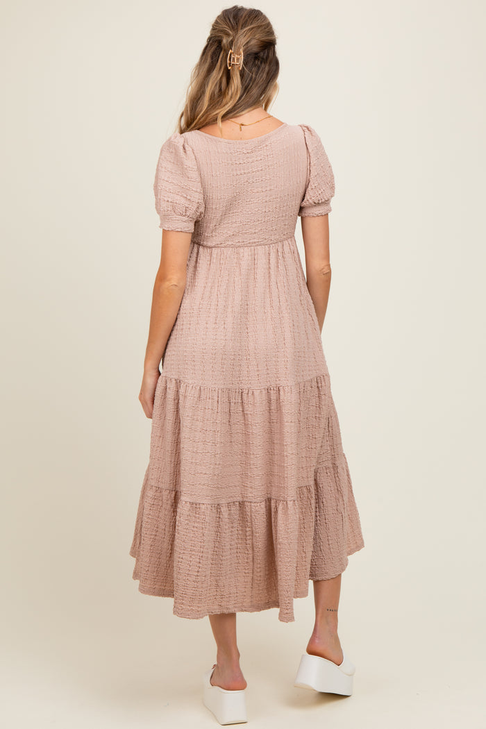 woman wearing a dusty pink maternity dress with puff sleeves and tiered skirt, showing the back view