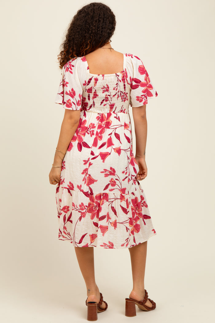 woman wearing a floral maternity dress with short sleeves and a smocked back, showing a baby bump from the back