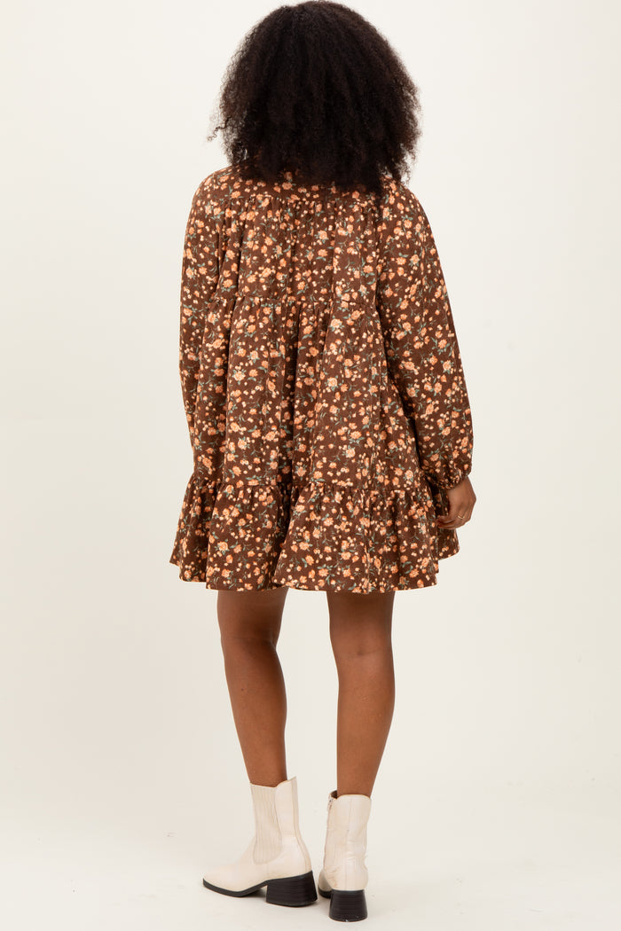 woman wearing a brown floral long sleeve dress with a tiered hem and a flared silhouette, seen from the back
