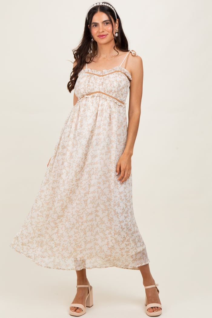 woman wearing a light pink floral maxi dress with spaghetti straps and ruffle details