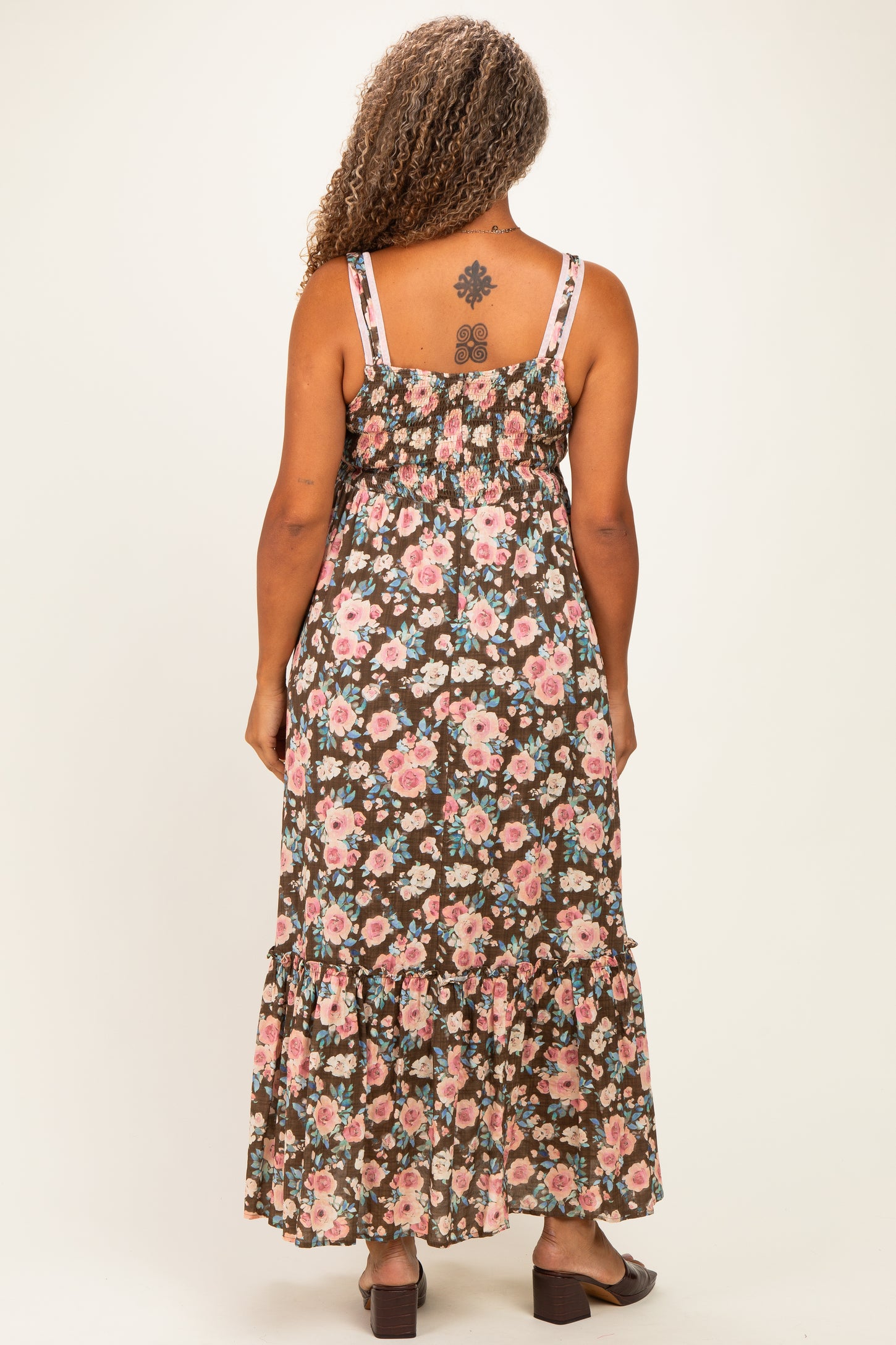 woman wearing a floral maxi dress with a smocked back and tiered ruffle hem, shown from the back