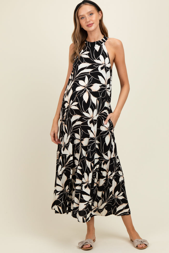 woman wearing a black and white floral print maternity maxi dress with pockets and a flowing silhouette, showcasing her baby bump