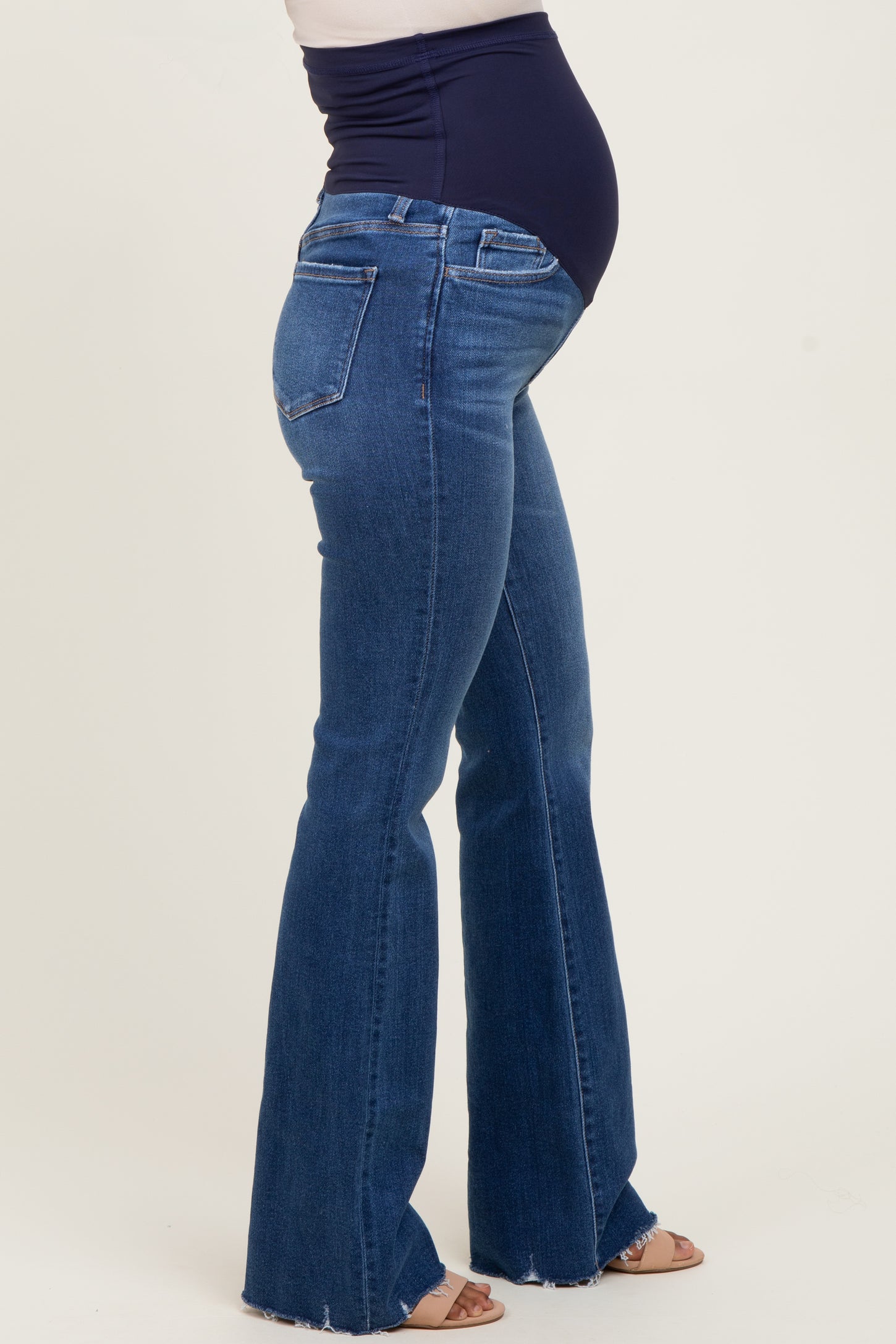 woman wearing dark blue maternity flared jeans, showing a visible baby bump