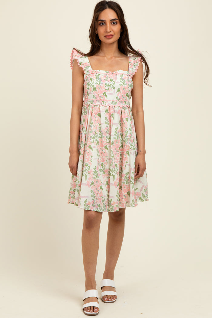 woman wearing a floral print sundress with square neckline and ruffled sleeves, posed against a neutral background