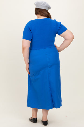 woman wearing a blue maternity plus dress with short sleeves and a fitted bodice, showing her back
