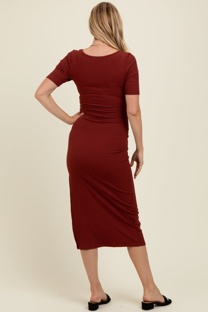 woman wearing a rust colored short sleeve ribbed maternity dress, view from the back