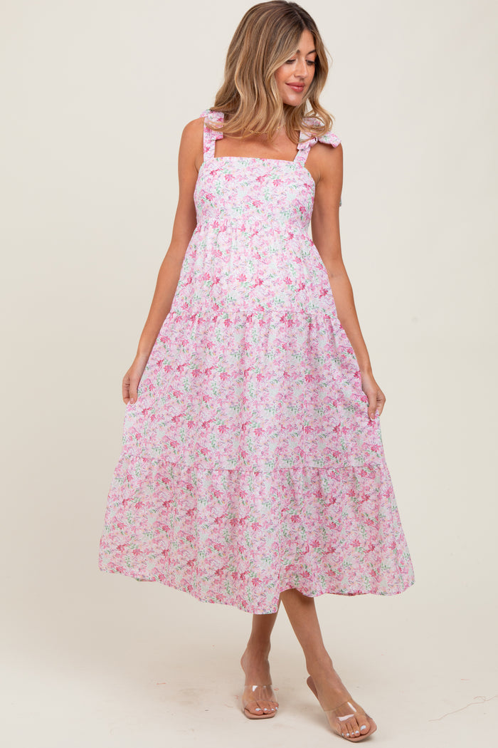 woman wearing a pink floral maternity dress with ruffled straps and a flowing skirt
